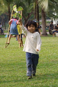 Portrait of boy holding pinwheel while walking on field