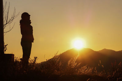 Silhouette person standing on field against sky during sunset