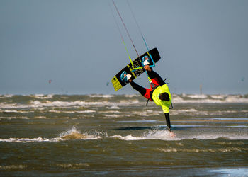 Kite surfer touches water with hand while being upside-down