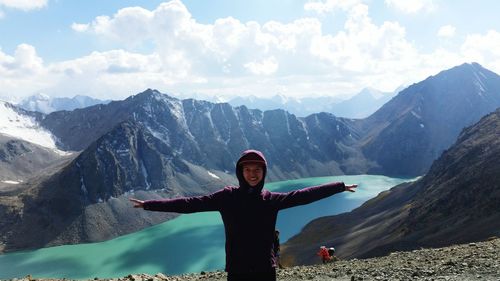 Portrait of happy young woman standing against valley during winter