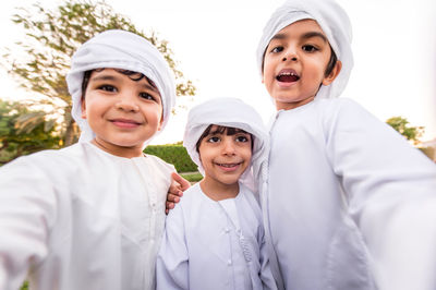 Cute brothers wearing traditional clothing standing in park