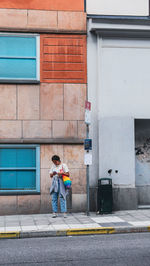 Full length of man standing on street against building