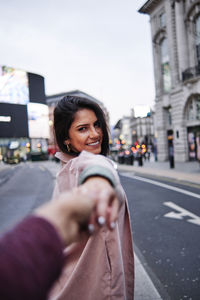 Portrait of beautiful woman standing on road in city