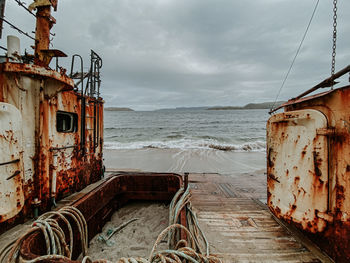 Abandoned boat by sea against sky