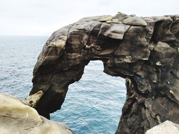 Rock formation in sea against clear sky