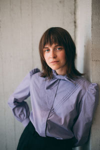 Portrait of woman standing against wall