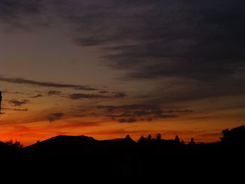 Silhouette landscape against dramatic sky during sunset