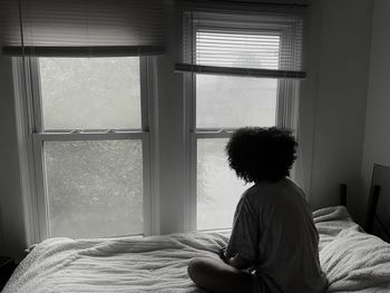 Rear view of woman looking through window