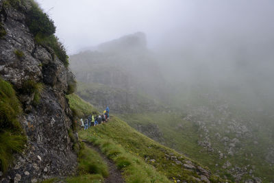 Hikers walking on mountain during foggy weather