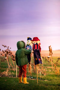 Rear view of friends standing on field against sky