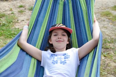 A beautiful girl lies in a yellow hammock on a background of blurred greenery.