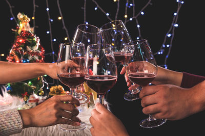 Cropped hands of friends toasting alcoholic drinks during christmas celebration
