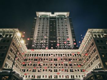 Low angle view of illuminated buildings against sky at night