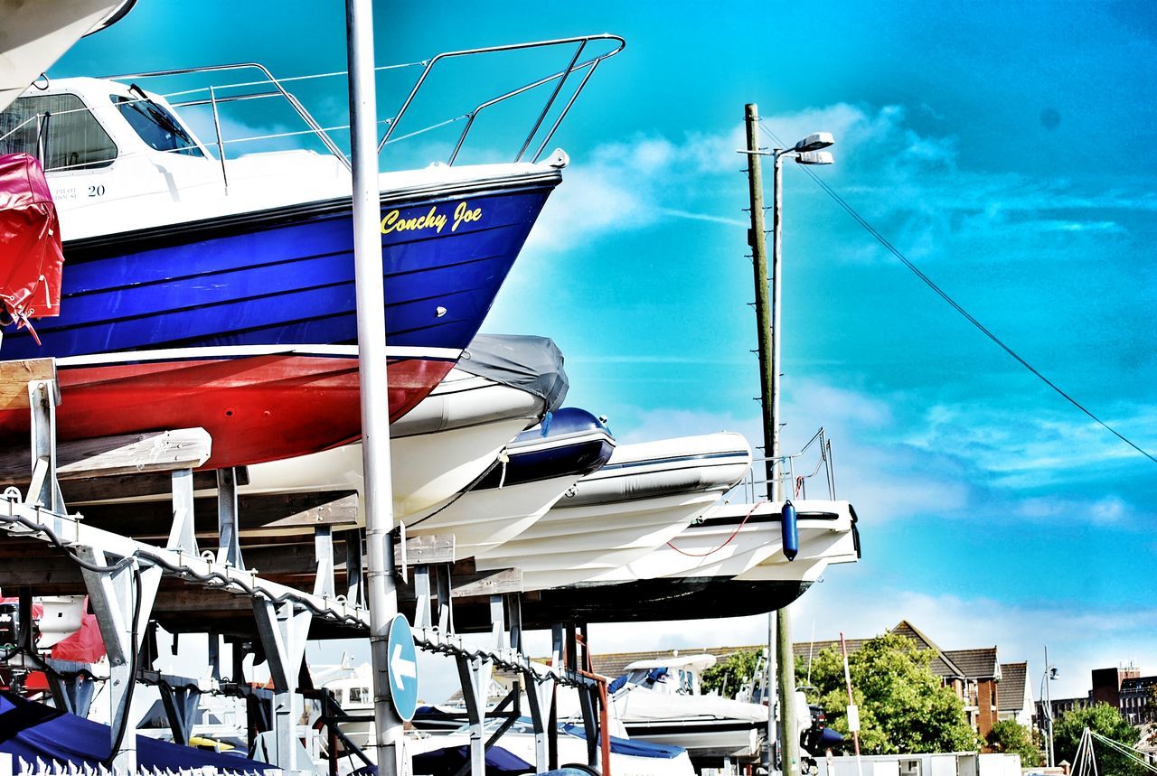 blue, sky, nautical vessel, moored, mode of transport, transportation, boat, day, cloud, cloud - sky, low angle view, outdoors, no people, flag, mast, group of objects, sunlight, hanging, in a row, rope