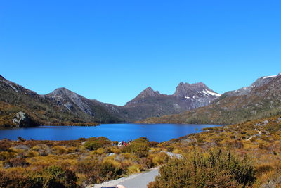 Scenic view of lake and mountains against clear blue sky