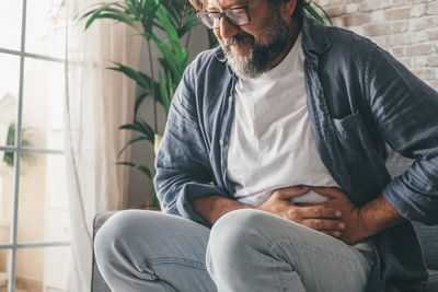 Midsection of man touching stomach at home