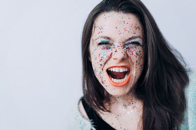 Close-up portrait of young woman with confetti against wall