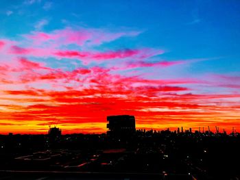 Silhouette buildings against dramatic sky during sunset
