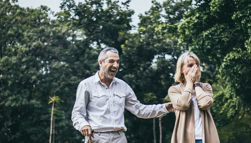 Man and woman standing by trees against plants