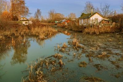 Abandoned house by lake against sky