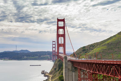 Golden gate bridge over river against cloudy sky