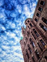 Low angle view of skyscrapers against cloudy sky