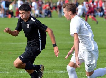 Full length of men playing soccer on field