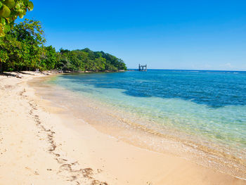 Scenic view of beach against clear blue sky