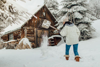 Rear view of young woman standing on snow field