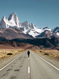 Rear view of man walking on road