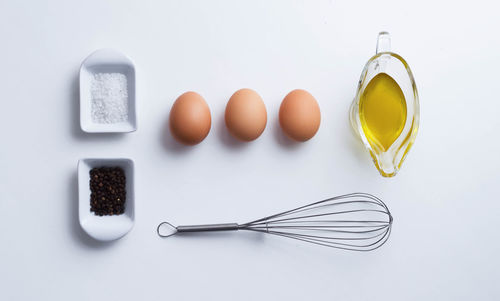 High angle view of eggs and oil and spice on white background