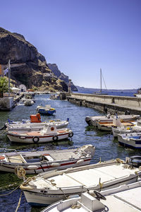 Sailboats moored at harbor against clear sky