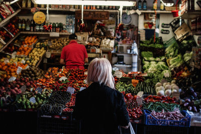 Rear view of woman with vegetables for sale at market stall