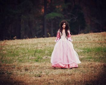 Portrait of woman standing on field in forest