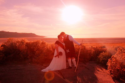 Romantic lesbians standing on field against sky on sunny day