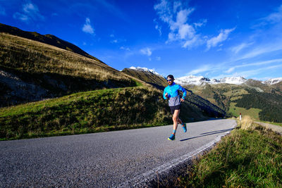 Rear view of man walking on road against sky