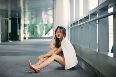 Portrait of young woman sitting by railing