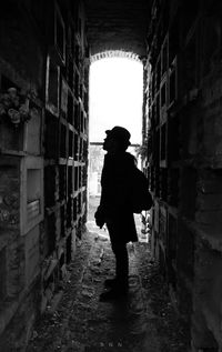 Full length rear view of silhouette woman walking in alley amidst buildings