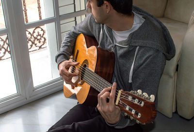Midsection of man playing guitar
