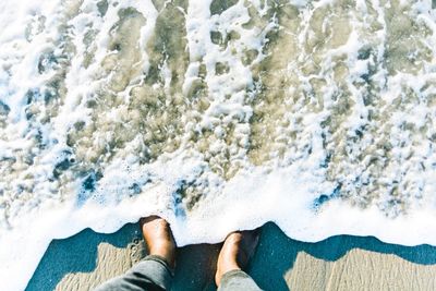 Low section of man standing on beach