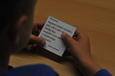 High angle view of man holding paper with text on table