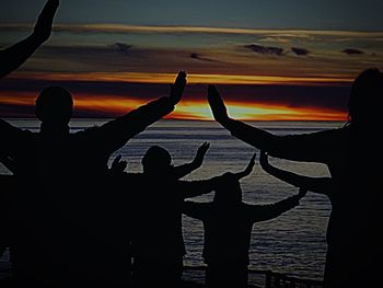 Silhouette people at airplane against sky during sunset