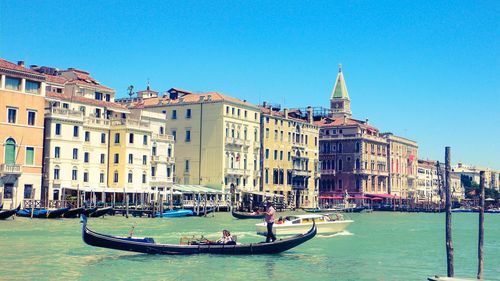 People in traditional gondolas against buildings