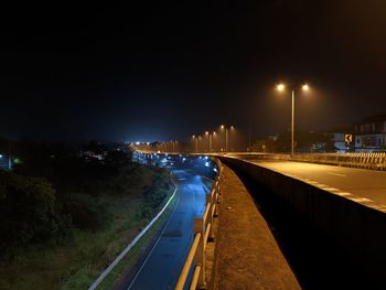 Vehicles on road in city against sky at night