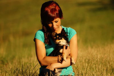 Young woman with puppy sitting on grassy field