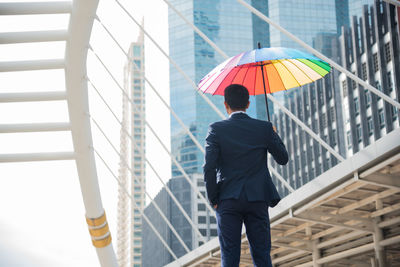 Rear view of man walking on umbrella