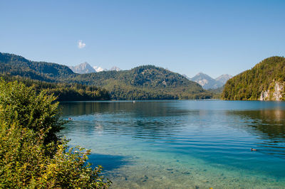 Scenic view of lake and mountains against clear blue sky