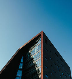 Low angle view of glass modern building against clear blue sky