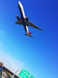 Low angle view of airplane flying against clear blue sky