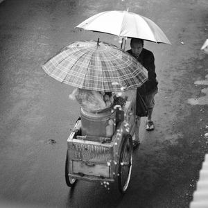 Rear view of man with umbrella on wet road